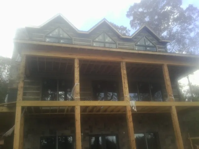Dormers and porch framing on a large log home under construction — Roof Coating work by our crew in Cambria