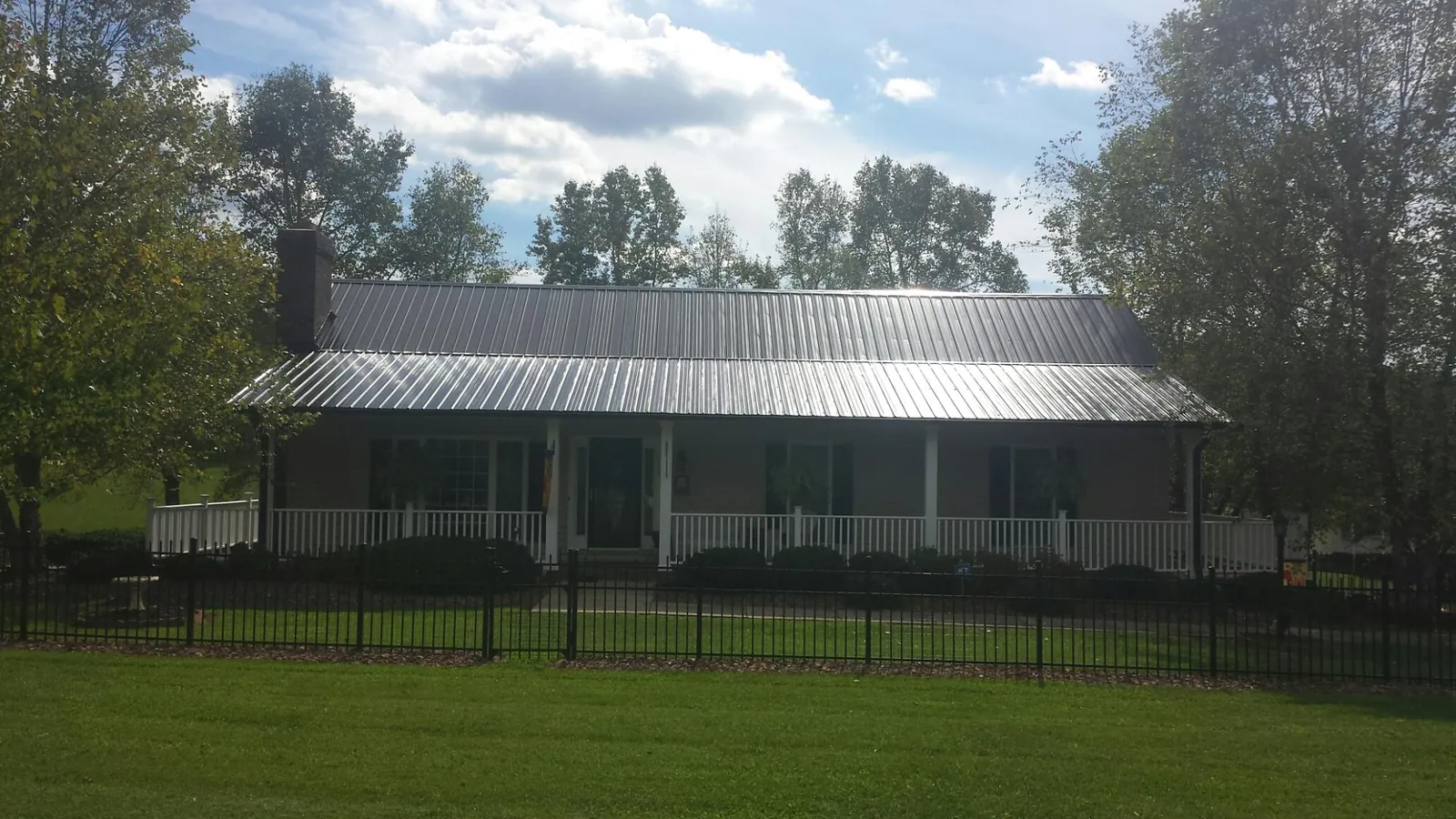 Gray metal roof on a brick ranch with a full width front porch — Gutter Guard Installation work by our crew in Cambria