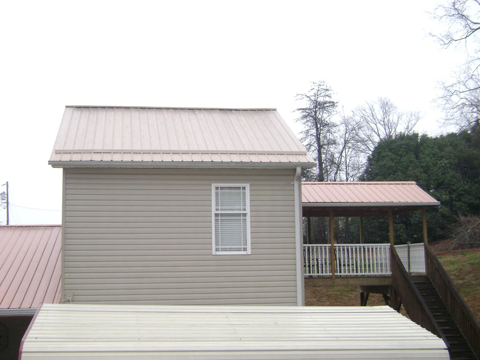 Tan metal roofs on a two story addition and attached porch, from a Roof Replacement job in Cambria