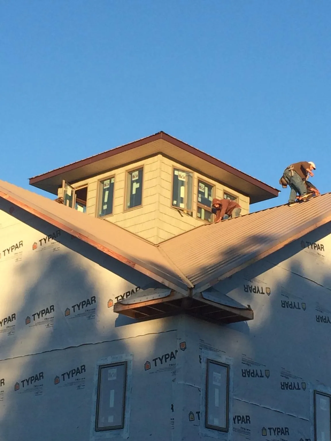 Roofers working around a rooftop cupola on a new metal roof at sunset — Roof Waterproofing in Cambria by Roofing Brothers